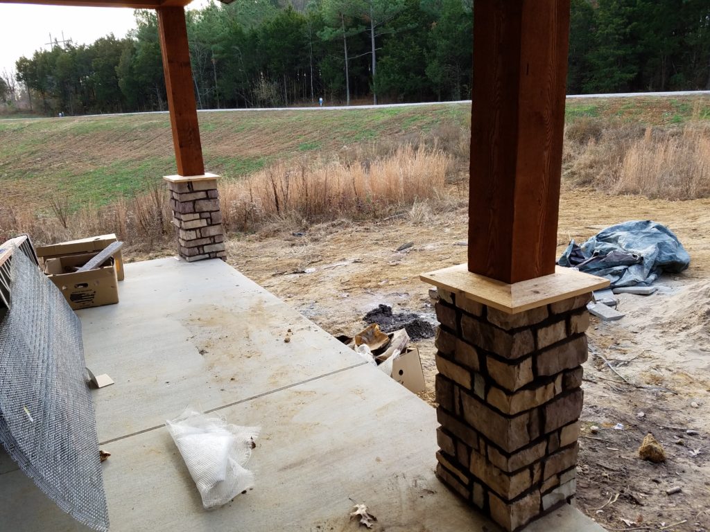 Wooden front porch posts with the stone work.