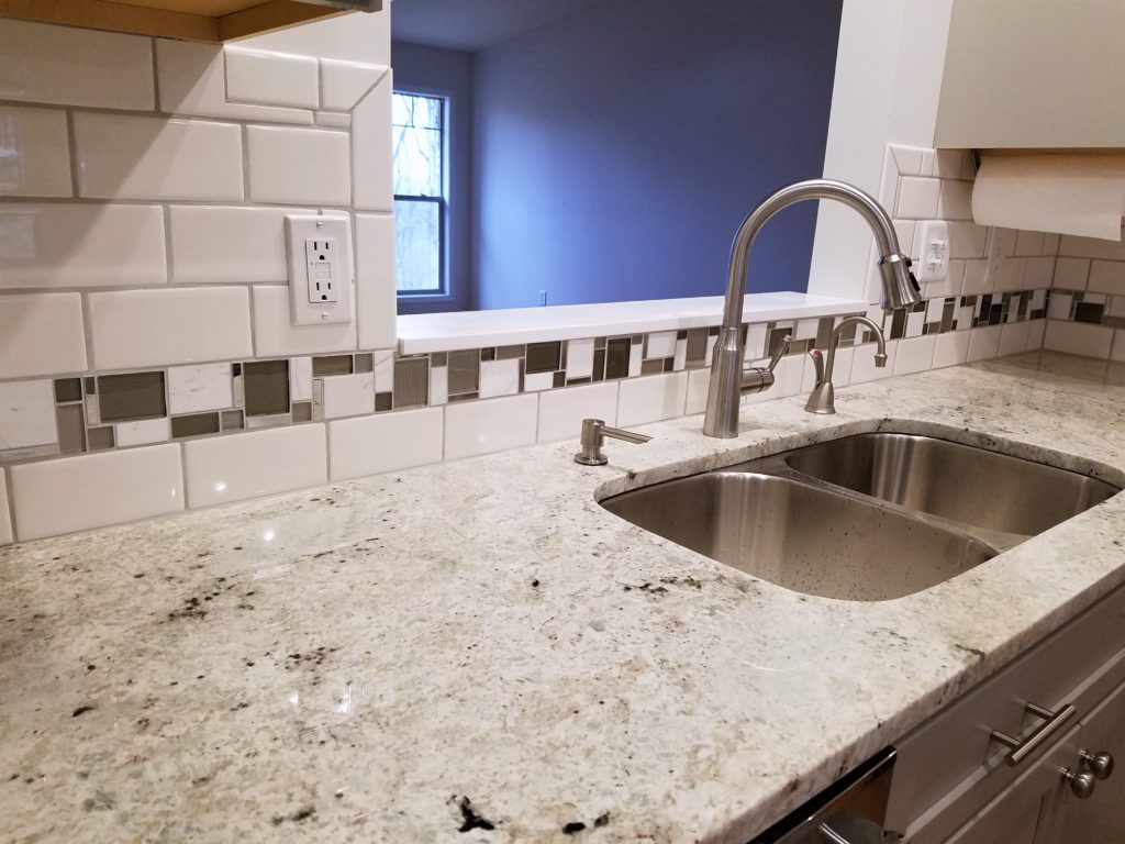 the kitchen sink and tile work on the wall.