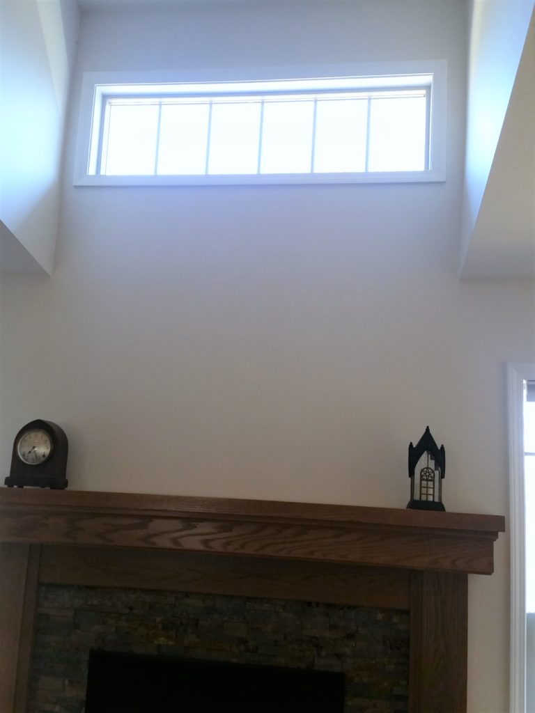 A closer view of the high window above the fireplace.