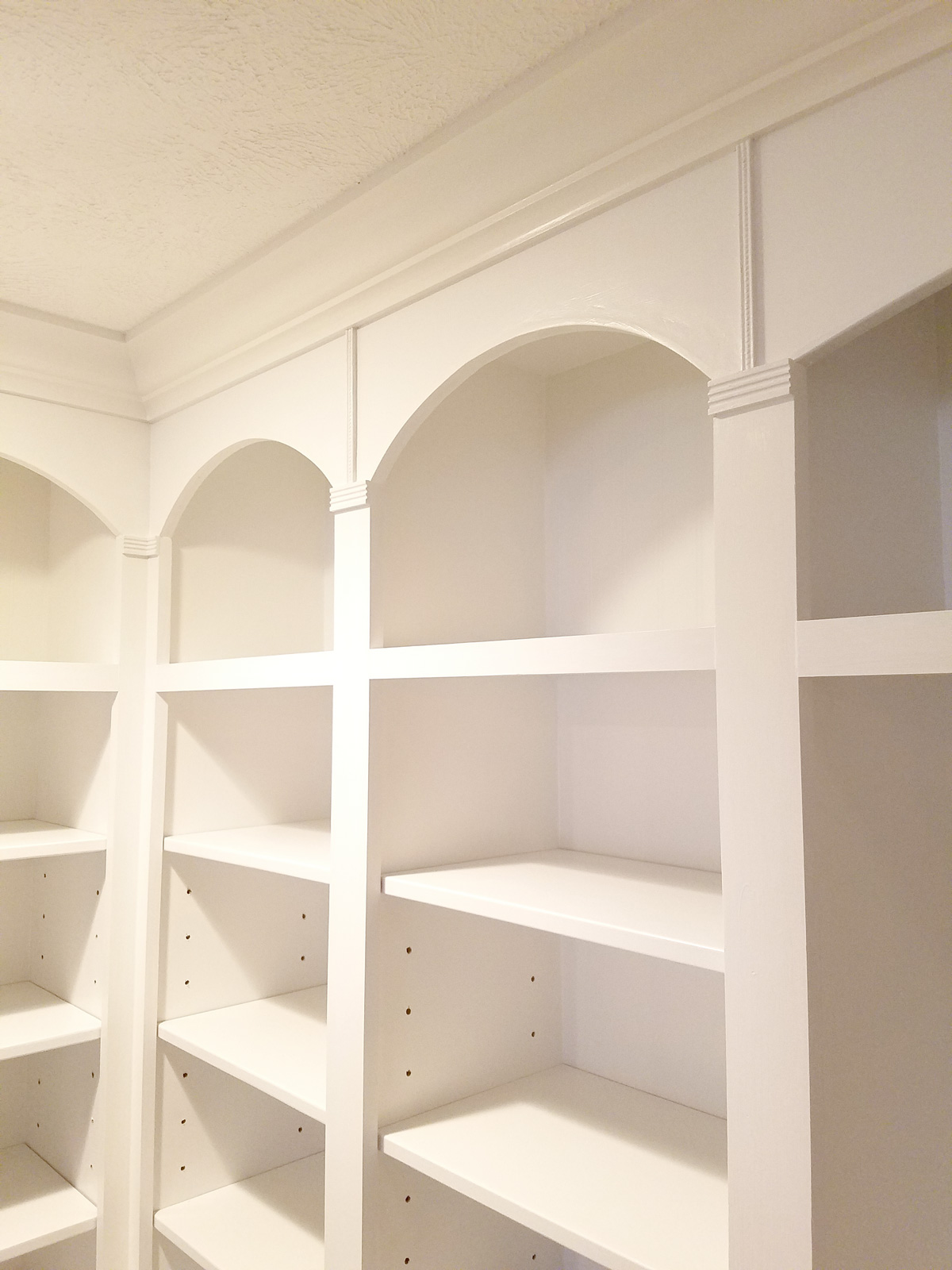 A large, white entertainment center with top shelves and bottom cabinets.