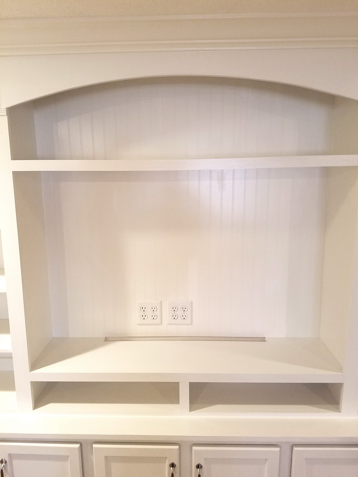 A large, white entertainment center with top shelves and bottom cabinets.